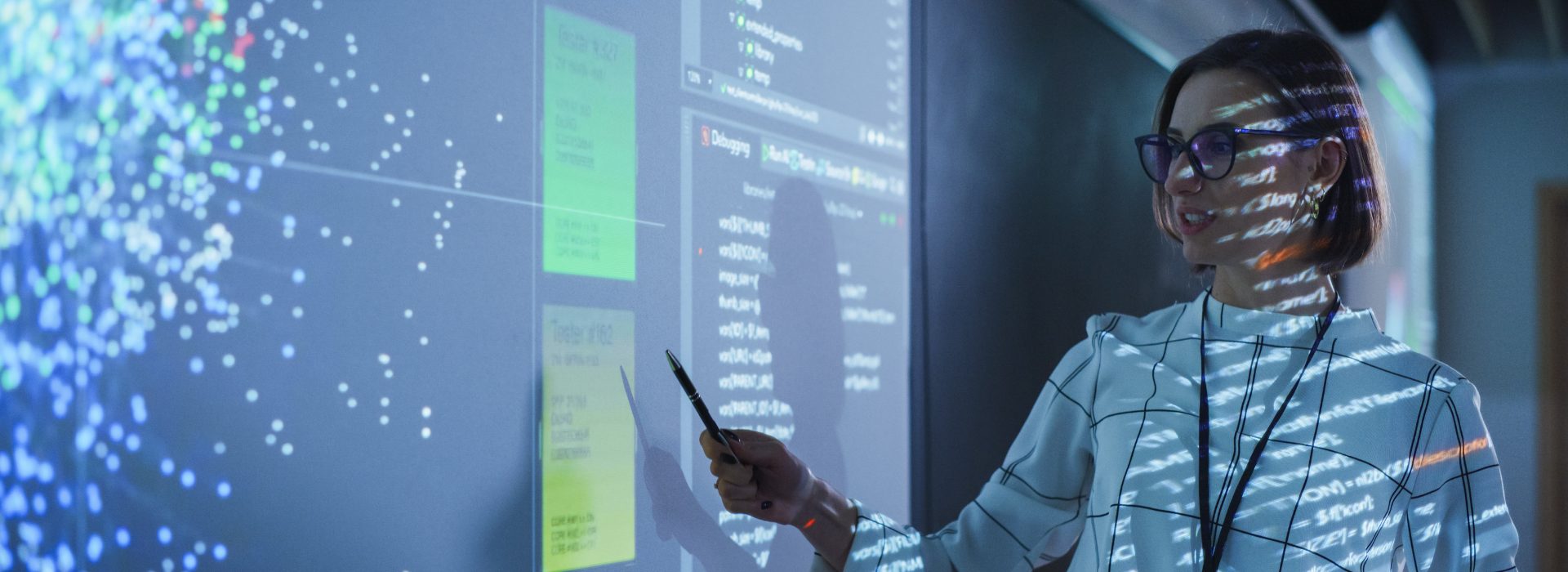 A teacher standing in front of a whiteboard with projected images about cybersecurity content.