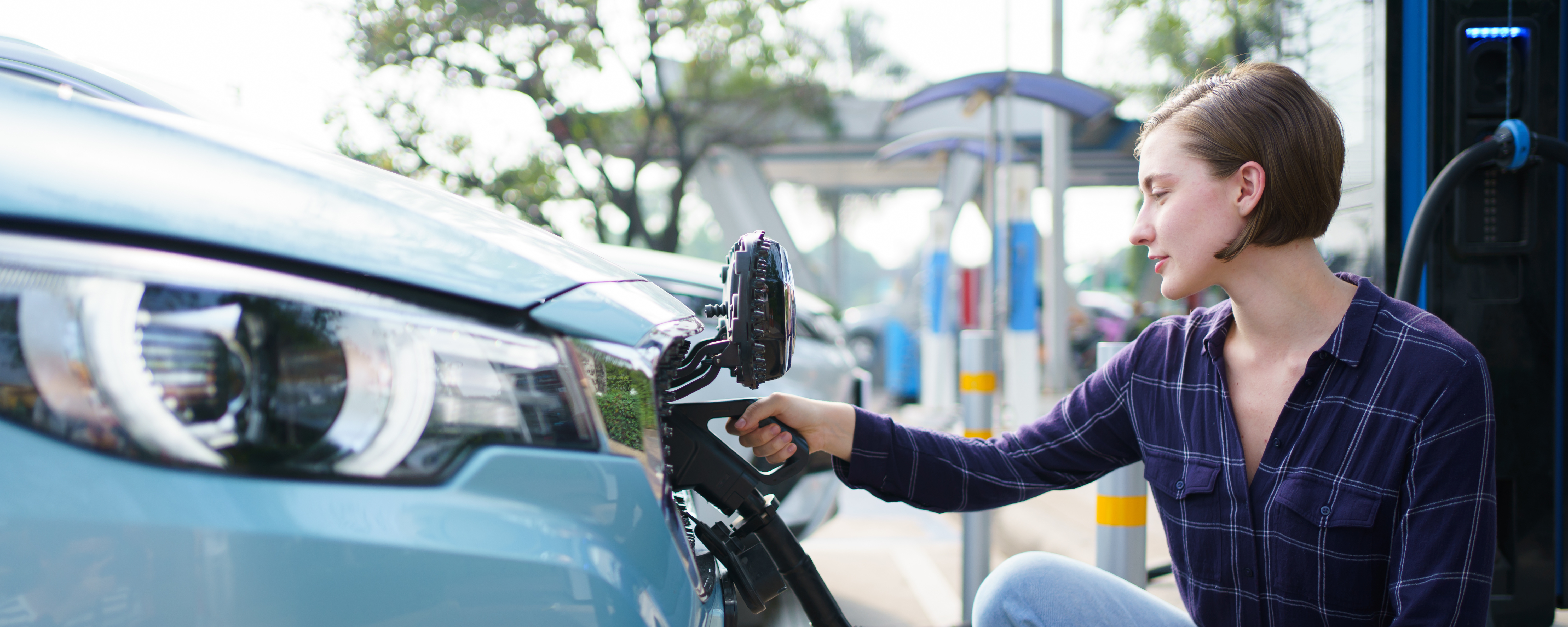 A woman inserts a charging port into an electric vehicle. 