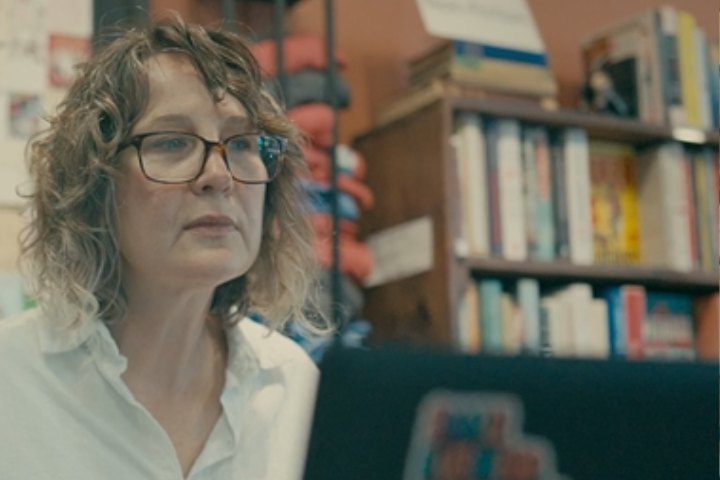 A woman looks at her laptop in a bookstore. 